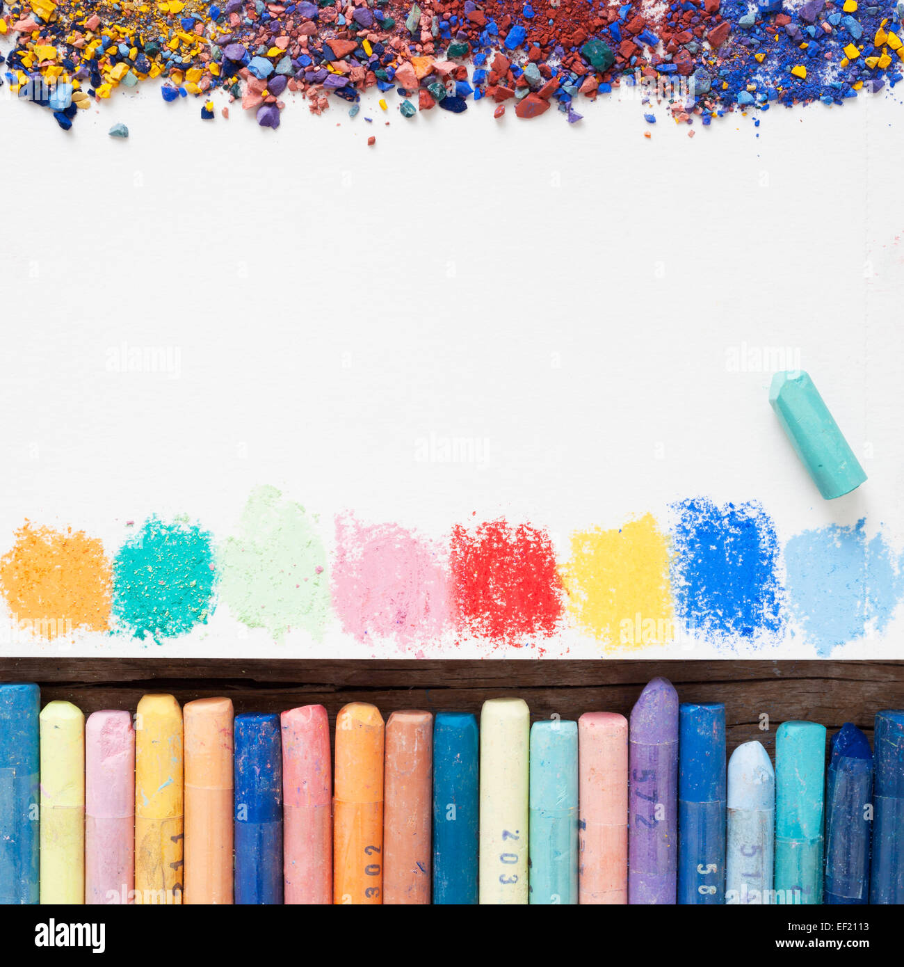 Matite di colore pastello e foglio di carta bianco di sketchbook con macchie di vernici e polvere di pigmento. Foto Stock