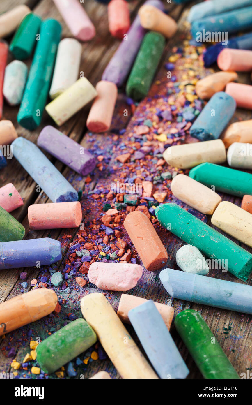 Raccolta di arcobaleno pastello colorato pastelli con polvere di pigmento su una vecchia scrivania in legno. Foto Stock