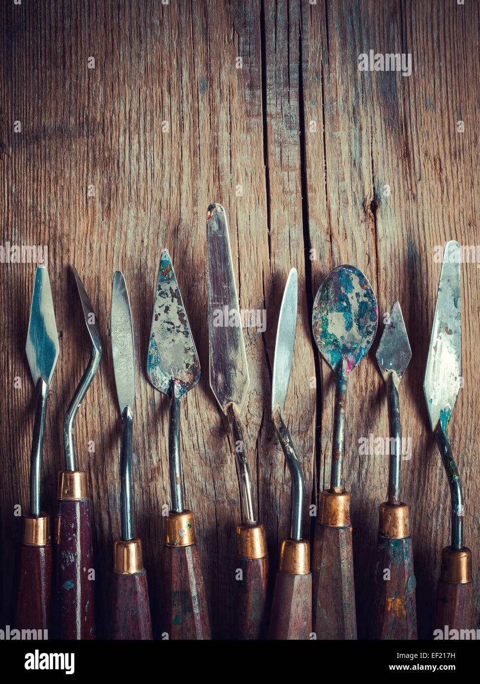 Serie di palette artista coltelli su legno vecchio tavolo rustico, retro stilizzata Foto Stock