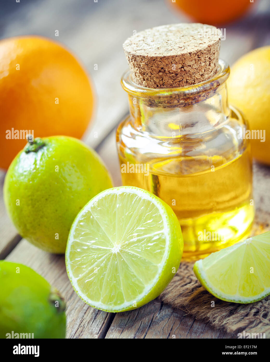 Olio essenziale di agrumi e fette di arancia, limone e frutta di lime sul vecchio tavolo in legno Foto Stock