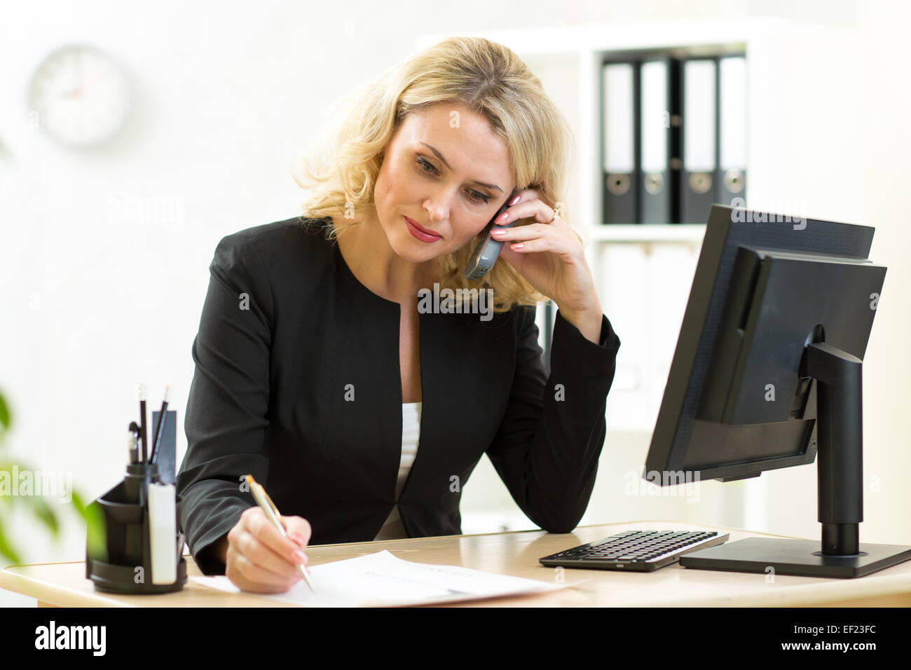 Imprenditrice che lavorano in ufficio. Dipendente di parlare al telefono e scrivere con la penna Foto Stock