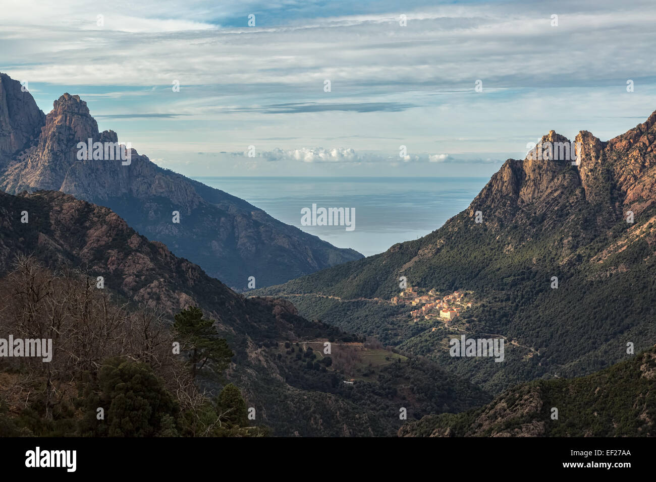 Il villaggio di Ota in Corsica con le montagne e il mare Mediterraneo dietro Foto Stock
