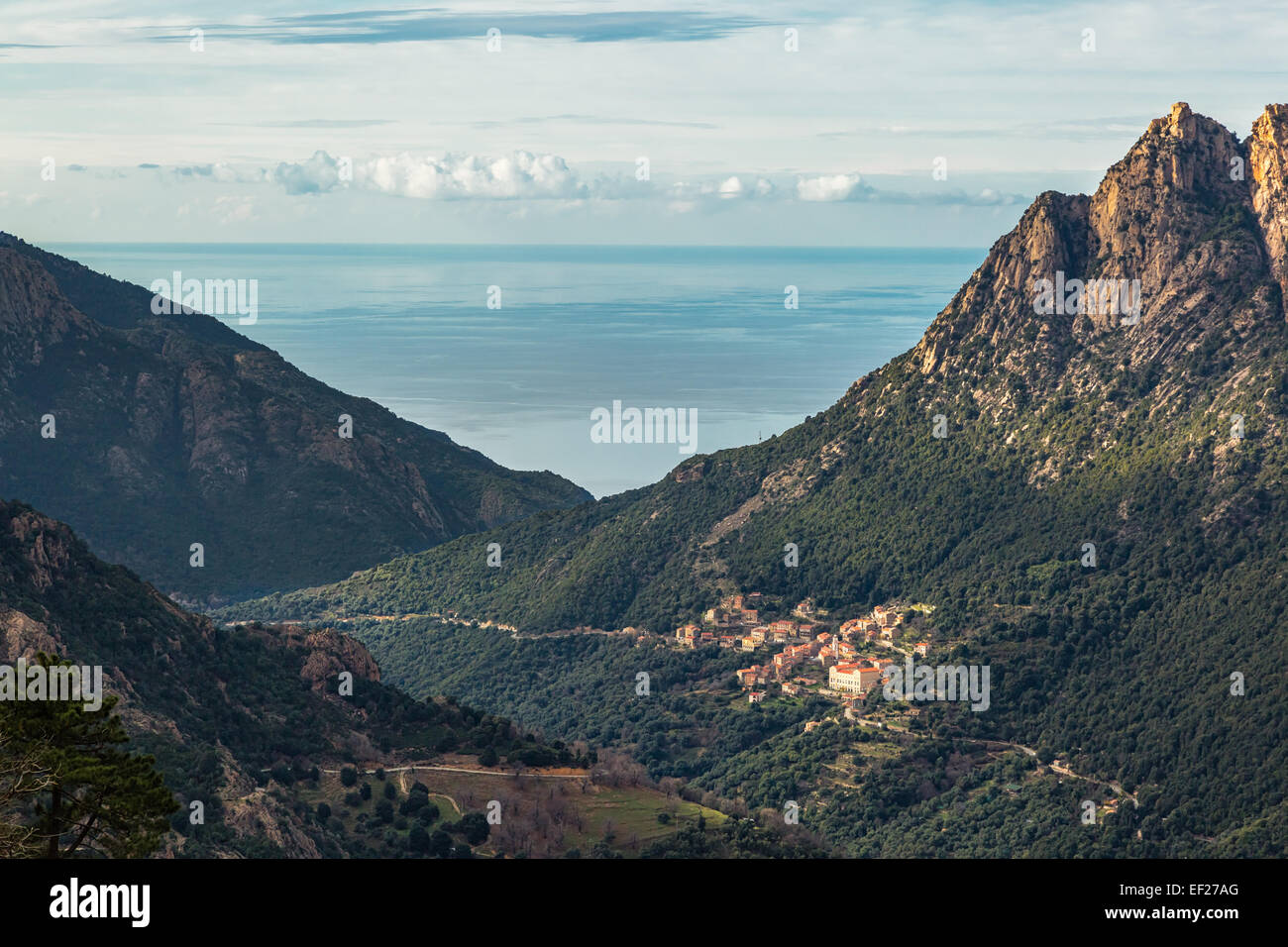 Il villaggio di Ota in Corsica con le montagne e il mare Mediterraneo dietro Foto Stock