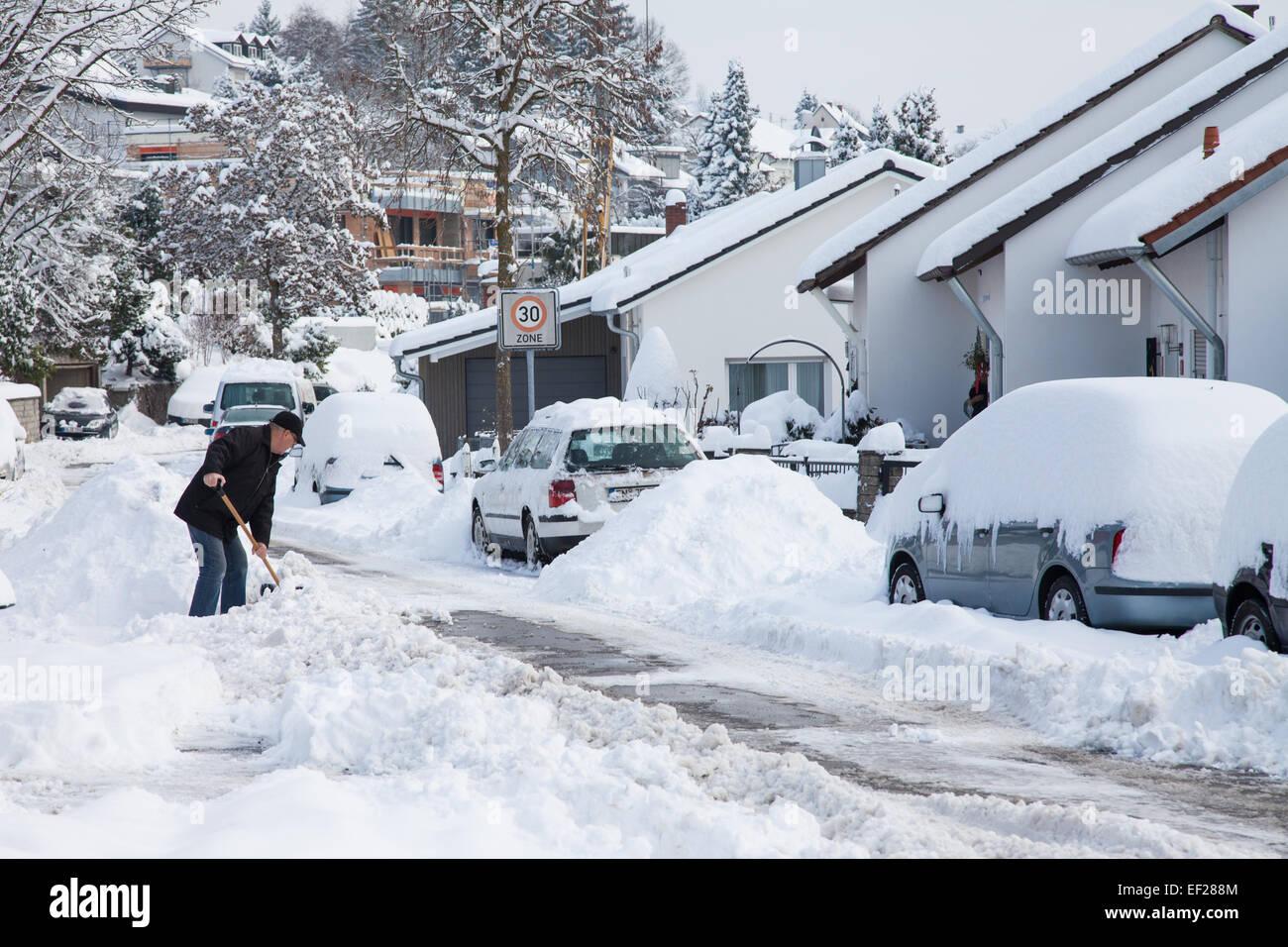 Uomo che pulisce il marciapiede dalla neve Foto Stock
