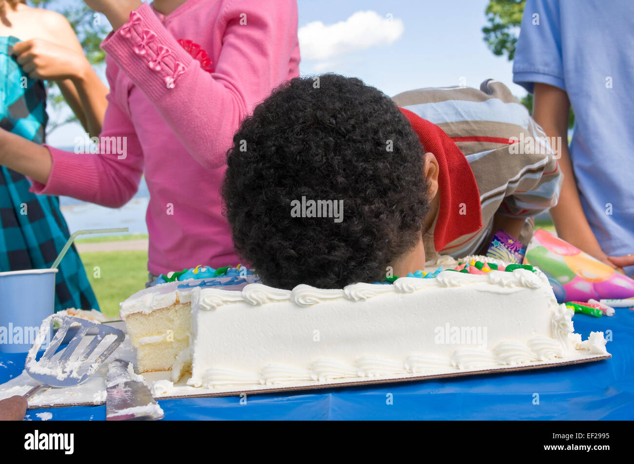 Bambino mettendo la sua faccia in una torta di compleanno Foto Stock