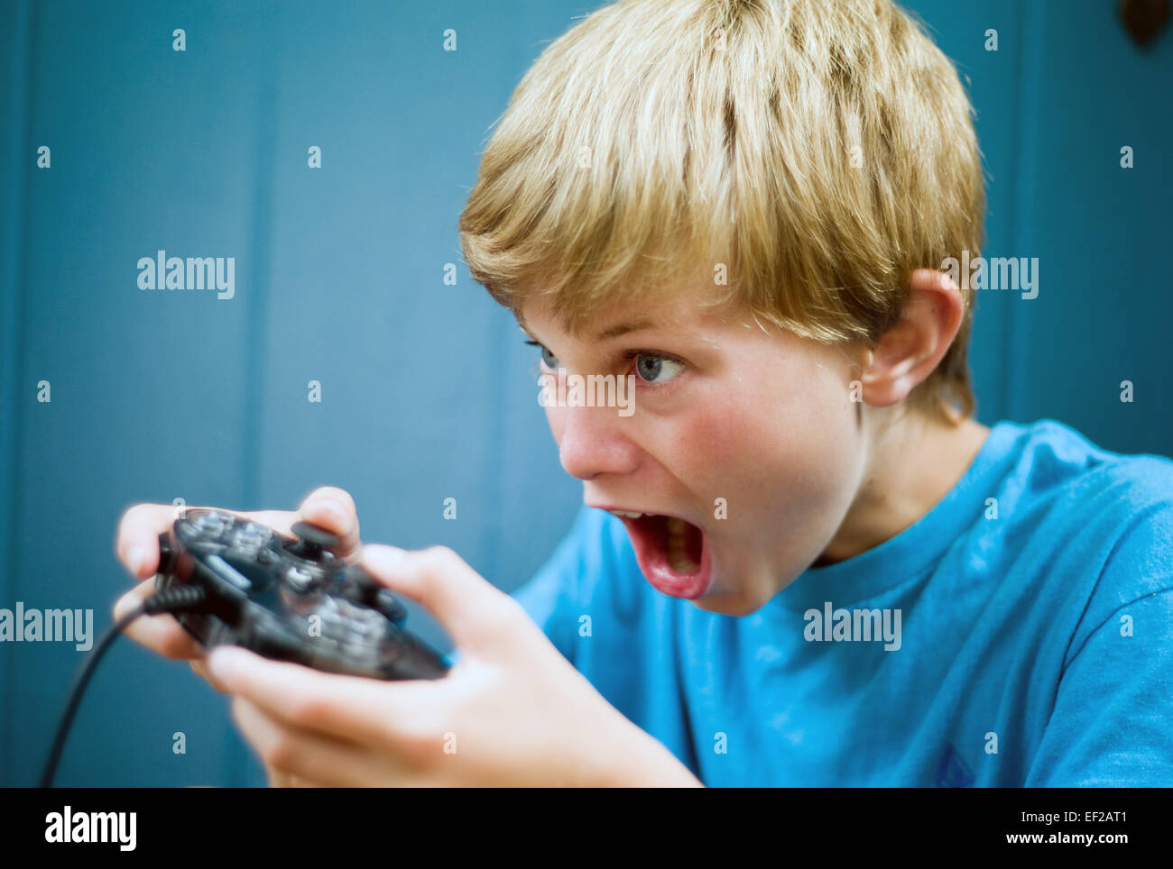 Ragazzo, 10-11-12-13, riproduzione di video gioco utilizzando il controller con concentrazione Foto Stock