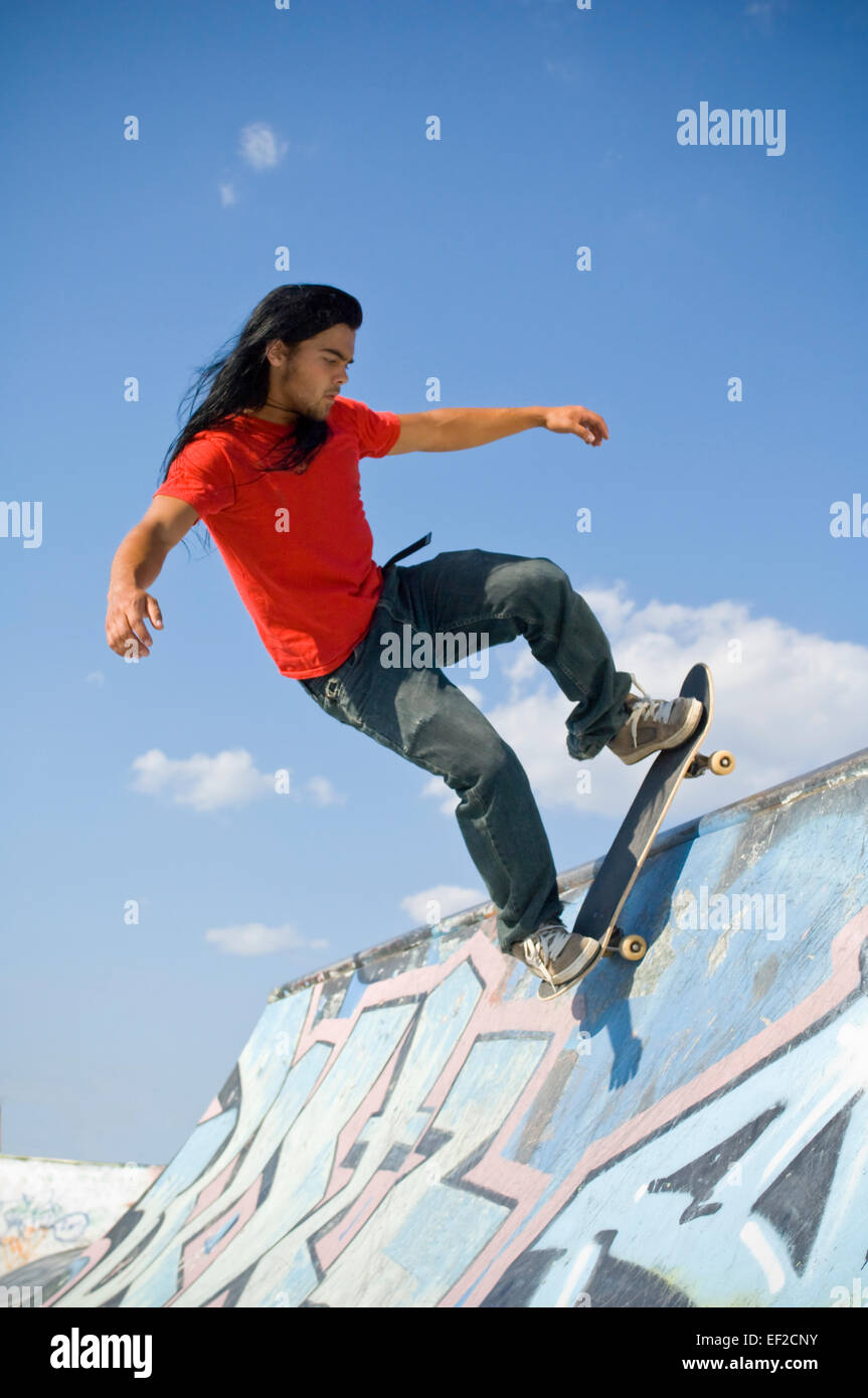 Un giovane uomo lo skateboard su una rampa da skateboard Foto Stock