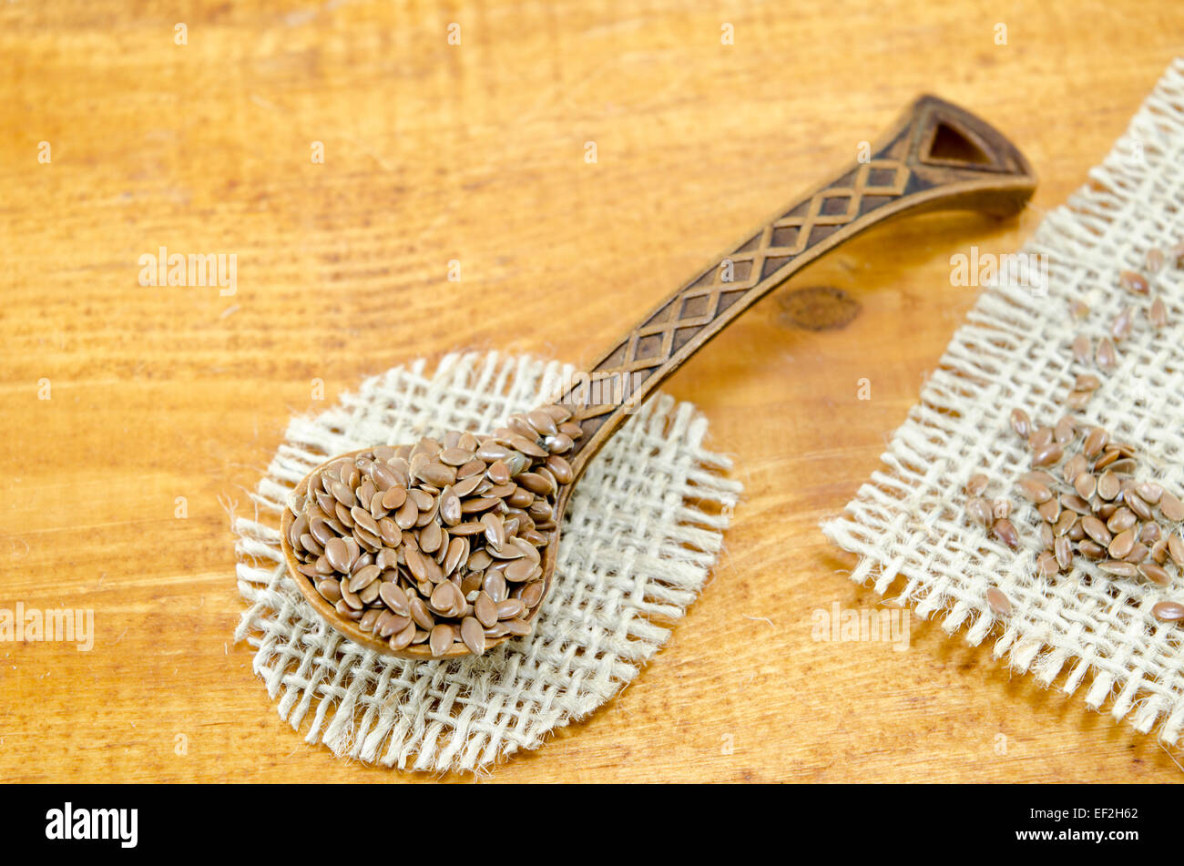 Inciso il cucchiaio di legno riempita con i semi di lino su una tovaglia vintage Foto Stock