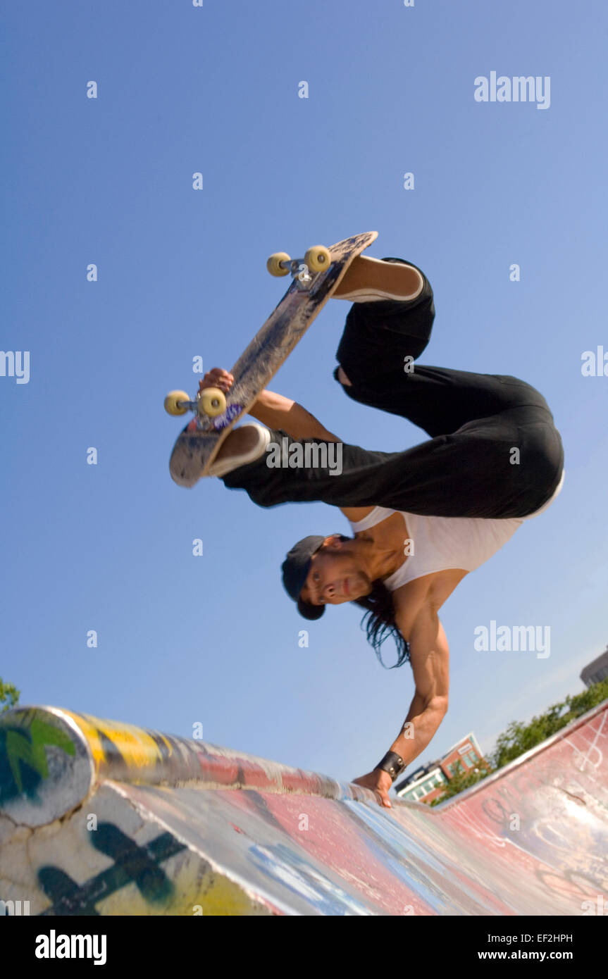 Guidatore di skateboard facendo antenne a un skate park Foto Stock