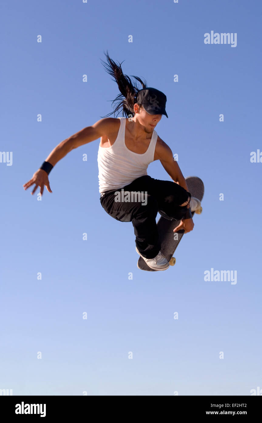 Guidatore di skateboard facendo antenne a un skate park Foto Stock