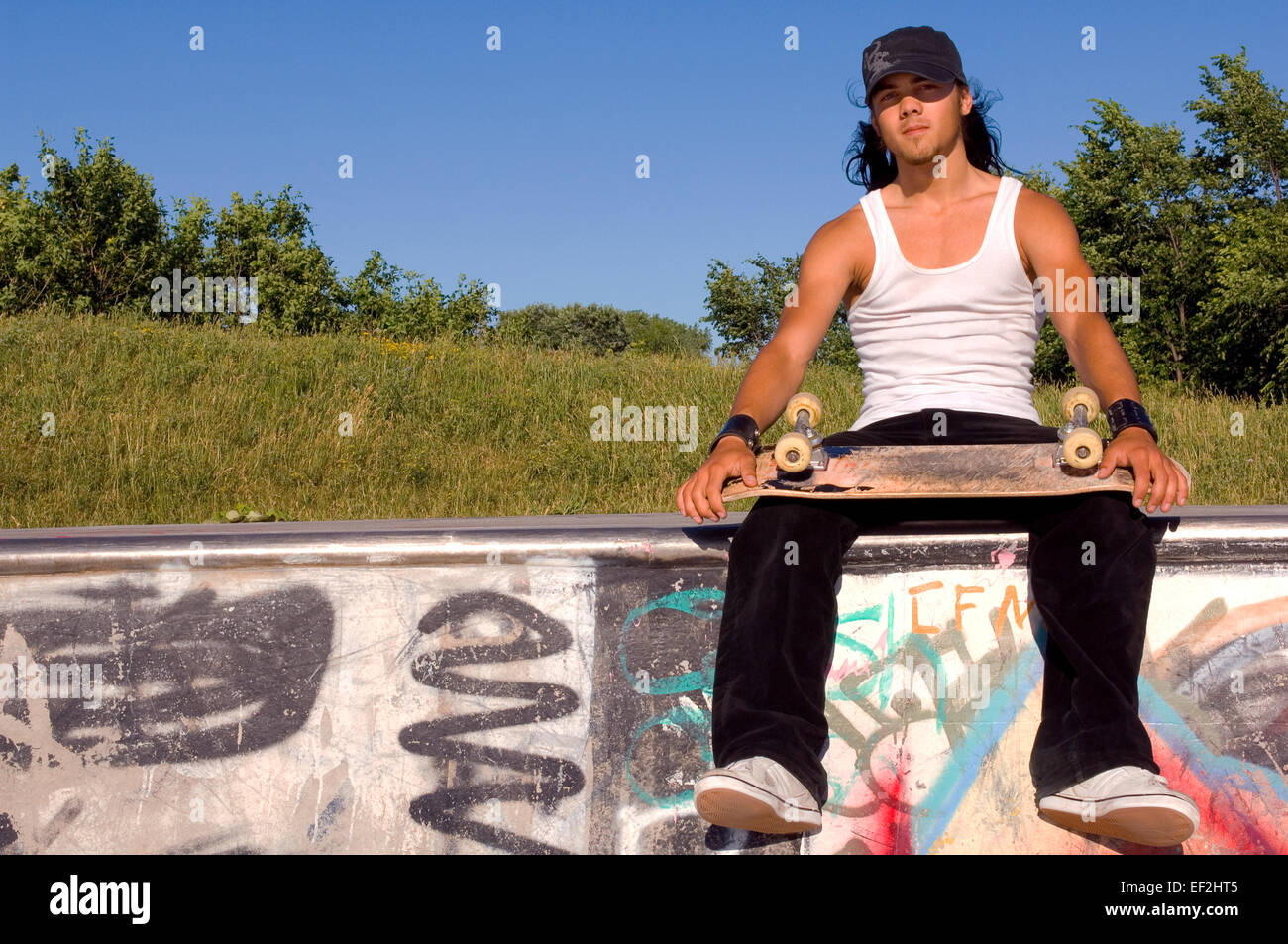 Guidatore di skateboard seduto a un skate park Foto Stock