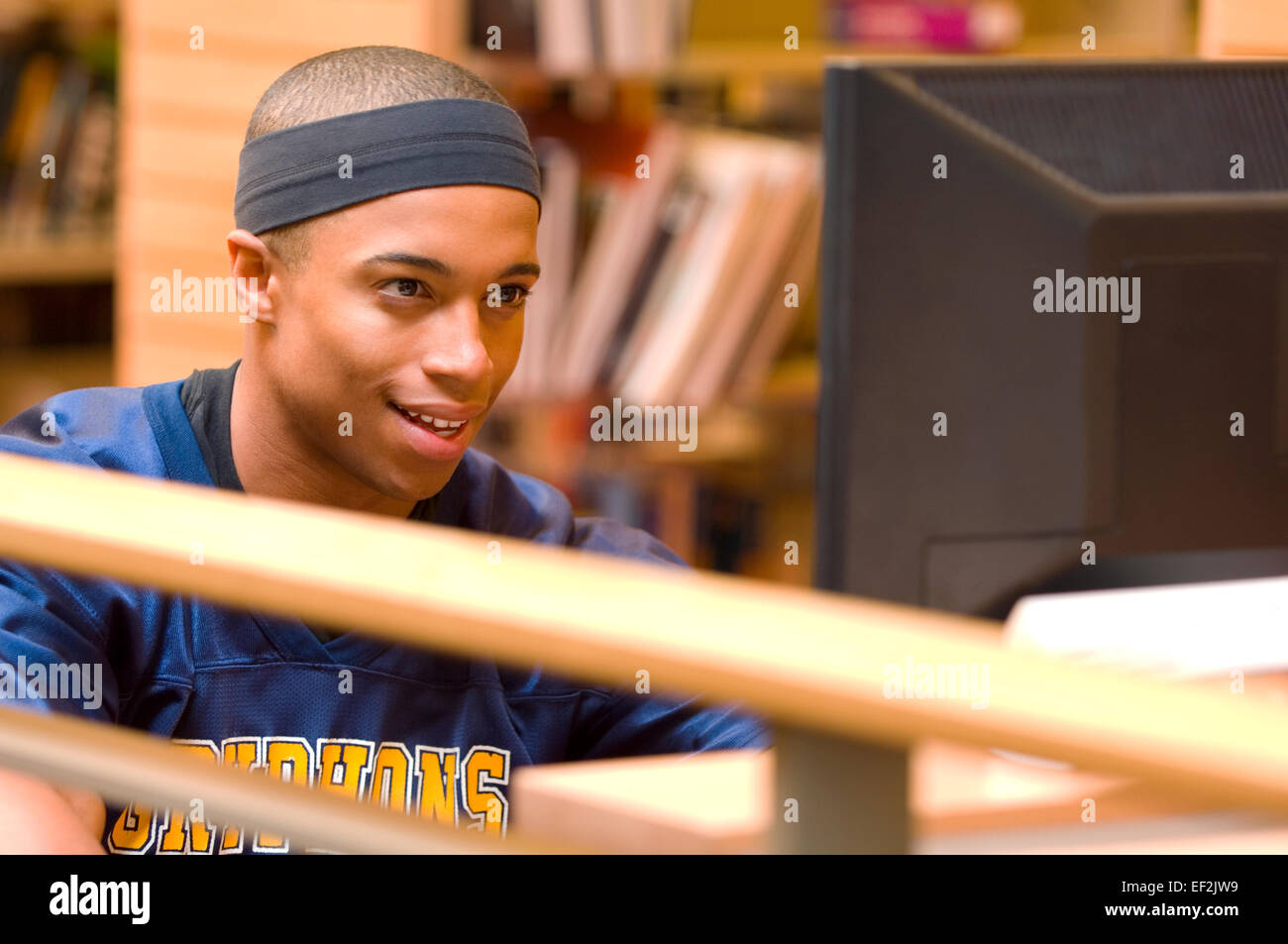Giovane uomo in una libreria in corrispondenza di un terminale di calcolatore Foto Stock