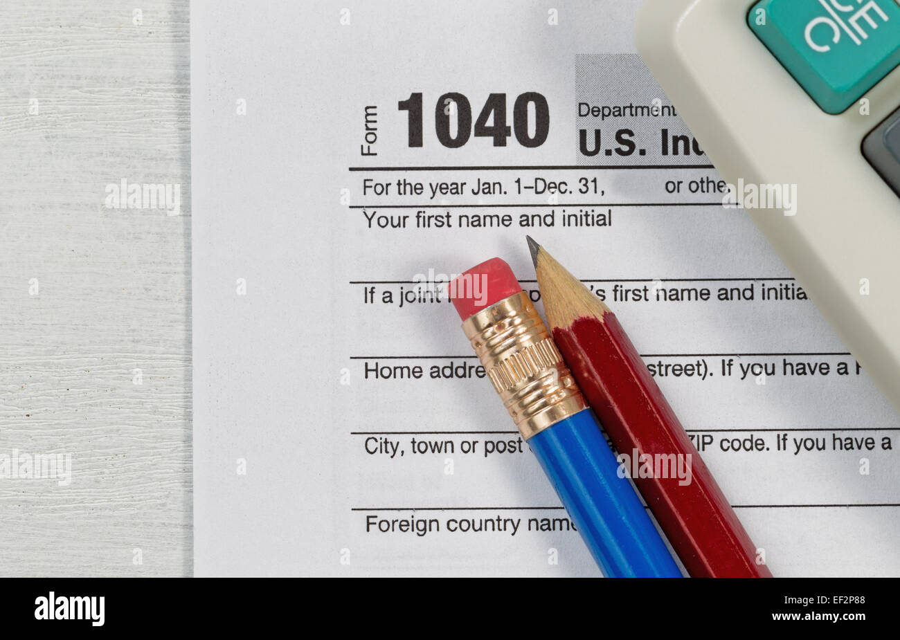 Close up U.S. Singolo modulo fiscale 1040 con parziale vecchia calcolatrice e matite sulla scrivania in legno. Focus sulle matite. Foto Stock