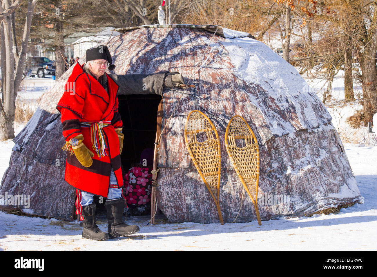 Uomo vestito come commerciante di pellicce si erge al di fuori di un wigwam Metis presso il festival di inverno in Cannington, Ontario Foto Stock