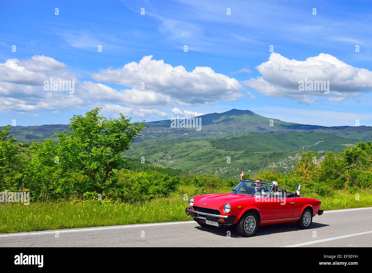 Fiat 124 Spider cabrio, classic car, sulla strada attraverso il paesaggio collinare, vicino a Radicofani, Toscana, Italia Foto Stock