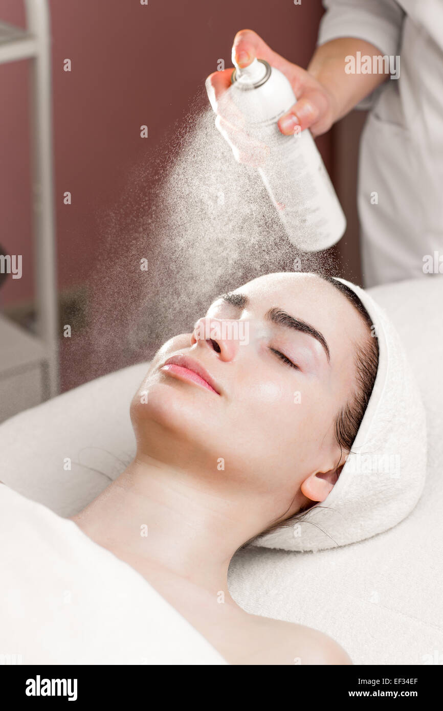 Maschera di siero da spruzzatura possibile sul giovane volto di donna in spa salone Foto Stock