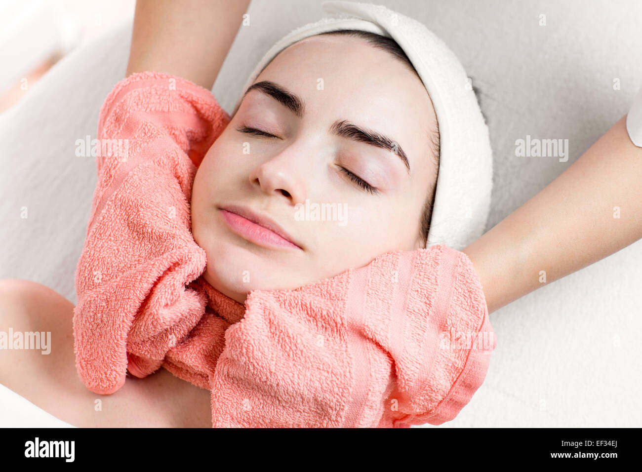 Giovane donna trattamento viso o massaggio con asciugamano Foto Stock