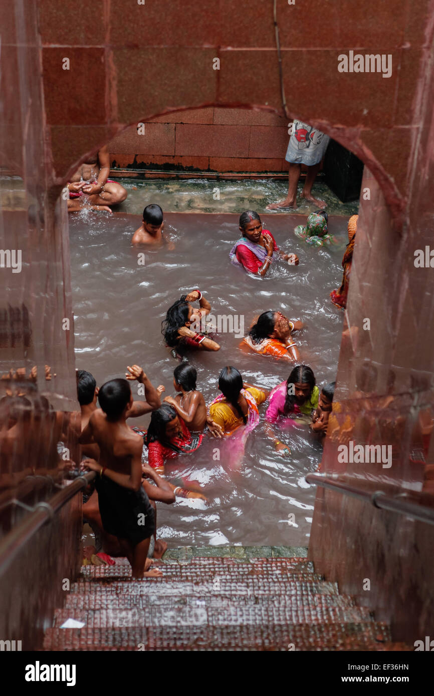 La gente che prende un bagno ad una sorgente calda, che è creduto avere qualità curative, all'interno del complesso del tempio di Lakshmi Narayan in Rajgir, Bihar, India. Foto Stock