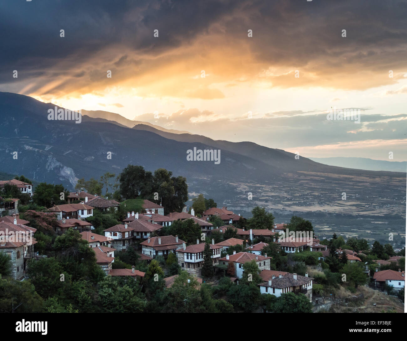 Questa fotografia cattura la tranquilla bellezza di Palaios Panteleimonas di sera. Il villaggio, situato sul Monte Olimpo in Grecia, è noto per le sue case in pietra e il fascino storico, con la luce soffusa della sera che migliora le sue vedute panoramiche e l'atmosfera tranquilla. Foto Stock