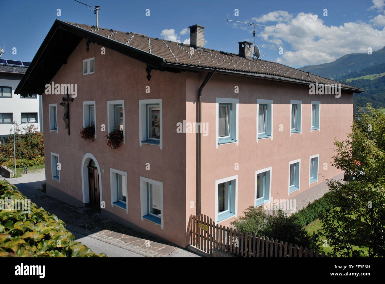 Questa è una rappresentazione di Terfens, una città situata in Austria, che mostra la sua architettura tradizionale e i dintorni panoramici, tra cui il Widum, una chiesa locale o un edificio religioso. Foto Stock
