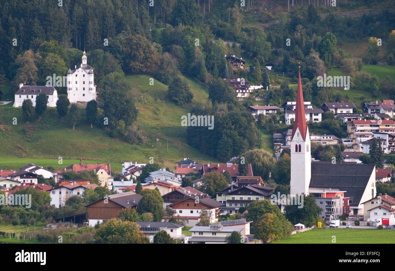 Questa fotografia raffigura la città di Volders, in Austria, con il castello di Aschach e una chiesa visibili sullo sfondo. L'immagine mette in risalto l'architettura storica e la bellezza naturale della zona. Foto Stock