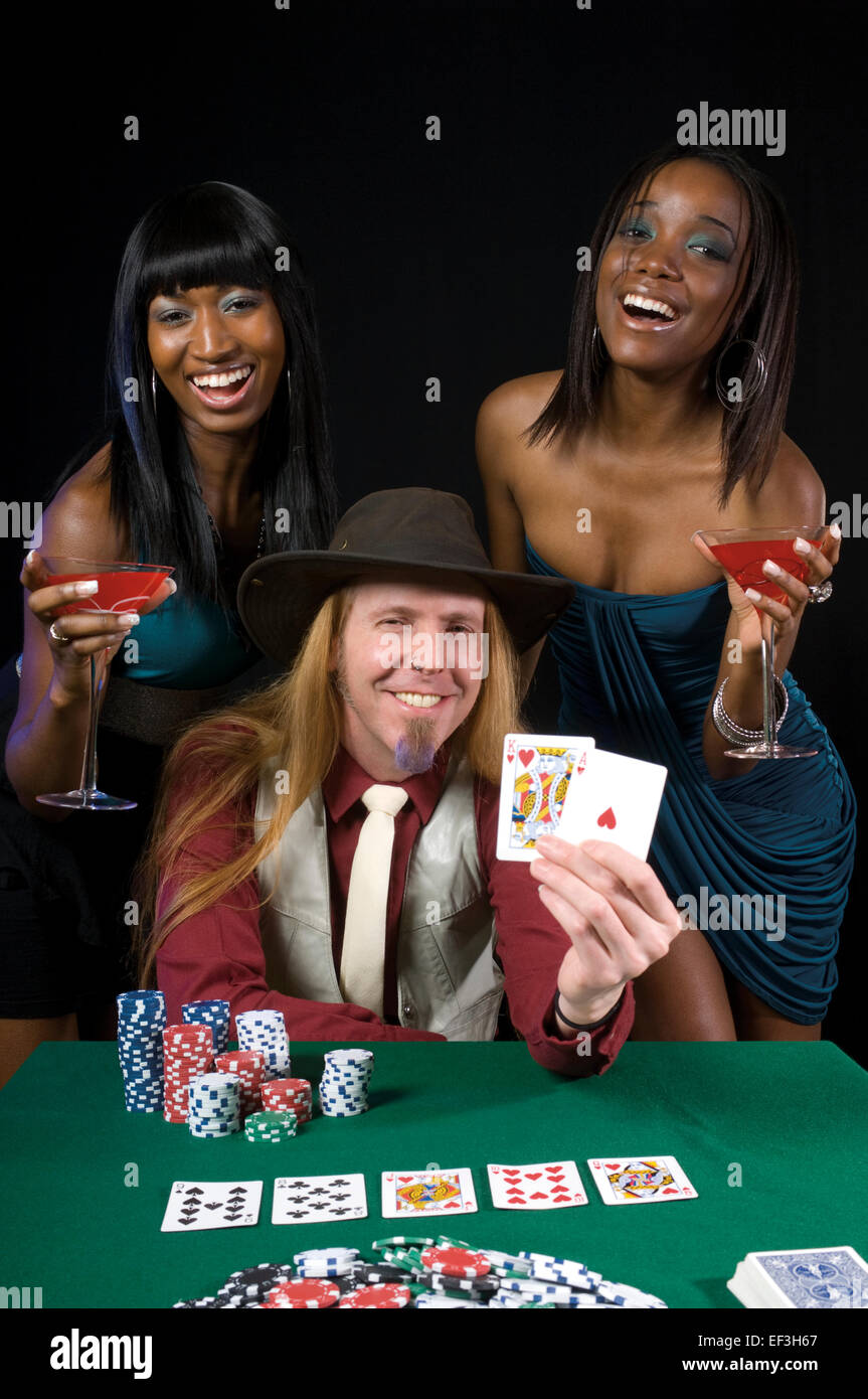 Due donna in piedi dietro un uomo giocando a poker Foto Stock