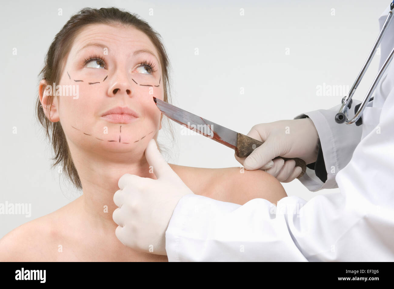 Medico tenendo un coltello insanguinato nella parte anteriore del volto di donna Foto Stock