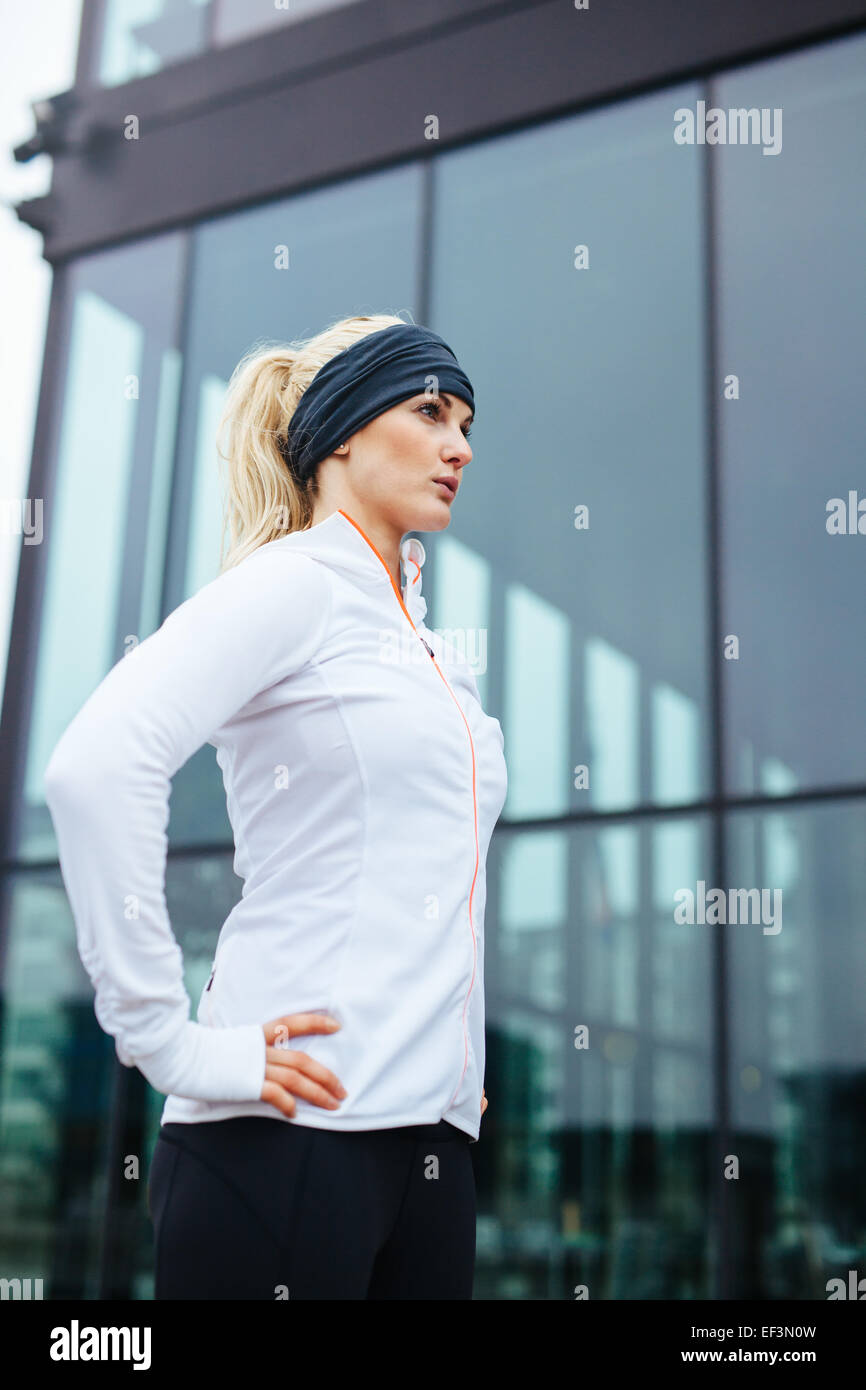 Colpo di un attraente giovane donna pronto per la sua sessione in esecuzione. Fitness atleta femminile all'aperto in piedi con le mani a fianchi Foto Stock