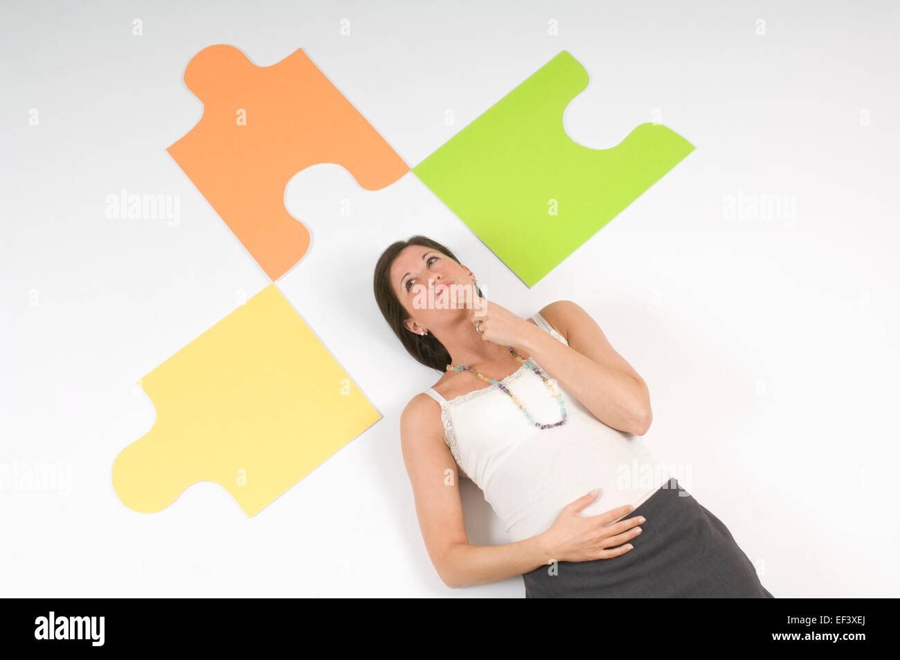 Donna sdraiata sul pavimento accanto a grandi pezzi di un puzzle Foto Stock