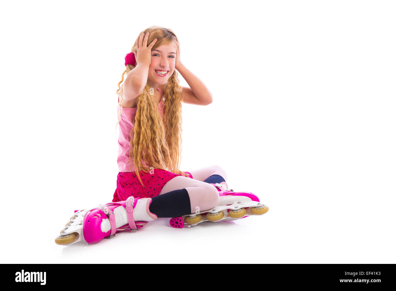Blonde pigtail pattino a rotelle ragazza seduta felice su sfondo bianco Foto Stock