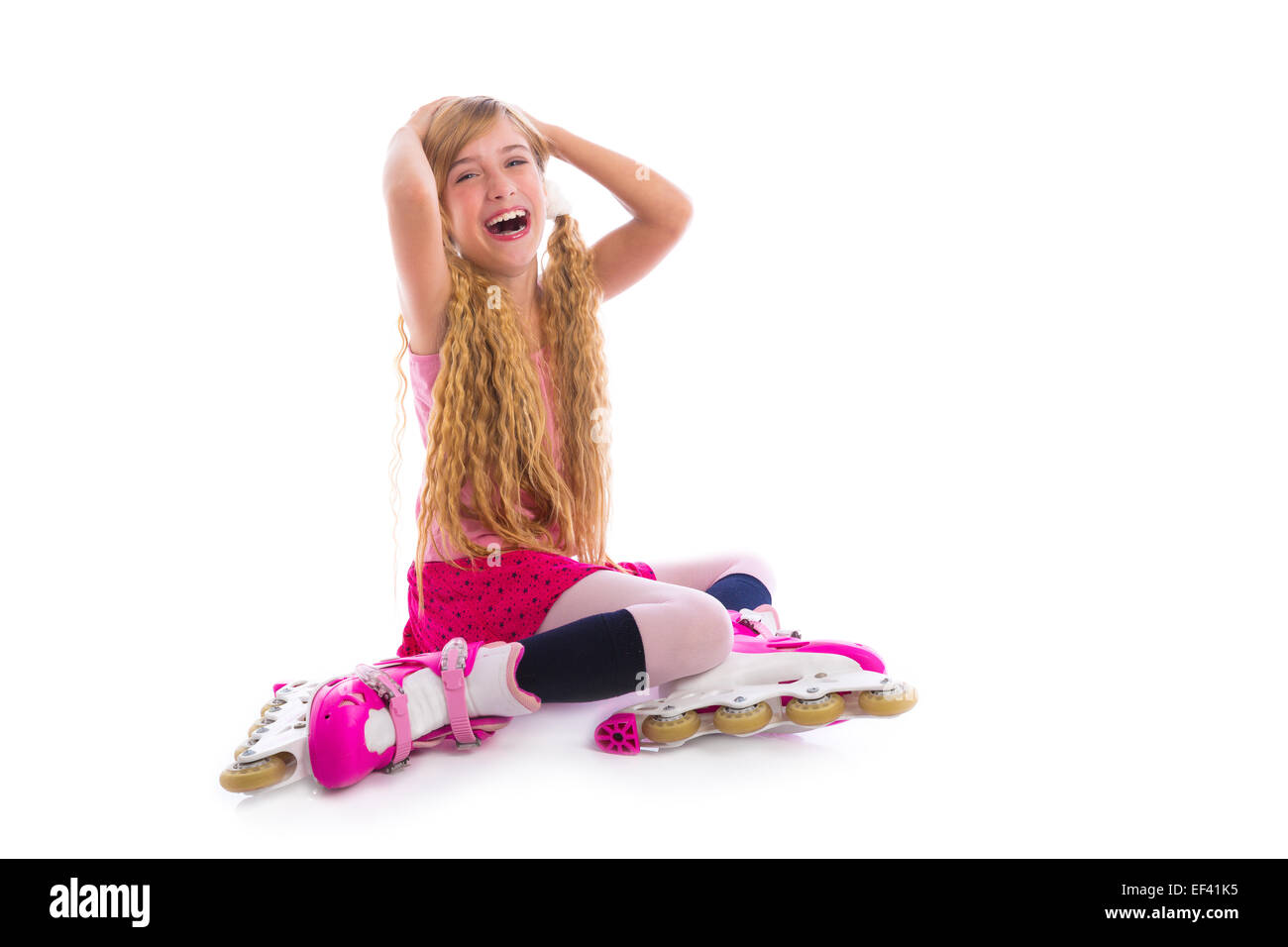 Blonde pigtail pattino a rotelle ragazza seduta ridendo felice su sfondo bianco Foto Stock