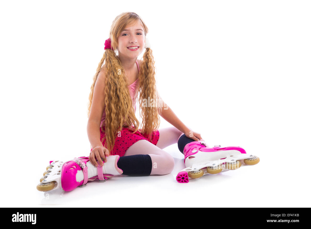 Blonde pigtail pattino a rotelle ragazza seduta felice su sfondo bianco Foto Stock