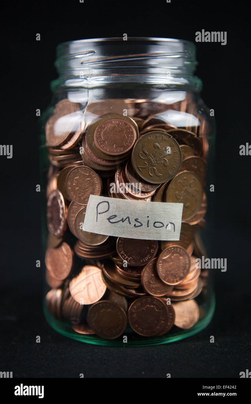 Un vaso di vetro azienda 1 e 2 pence monete con una etichetta dicendo "pensione". Foto Stock
