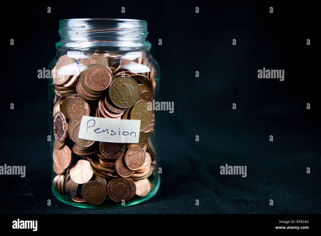 Un vaso di vetro azienda 1 e 2 pence monete con una etichetta dicendo "pensione". Spazio di testo a destra. Foto Stock