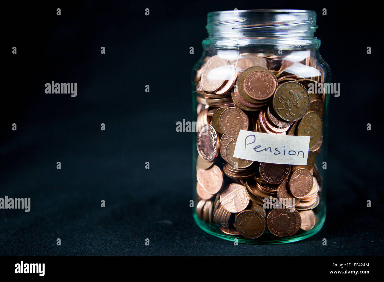 Un vaso di vetro azienda 1 e 2 pence monete con una etichetta dicendo "pensione". Spazio di testo a sinistra. Foto Stock
