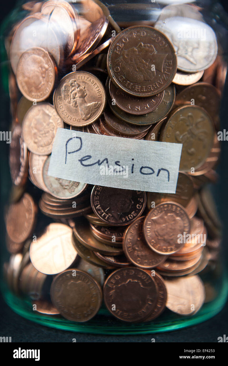 Un vaso di vetro azienda 1 e 2 pence monete con una etichetta dicendo "pensione". Foto Stock