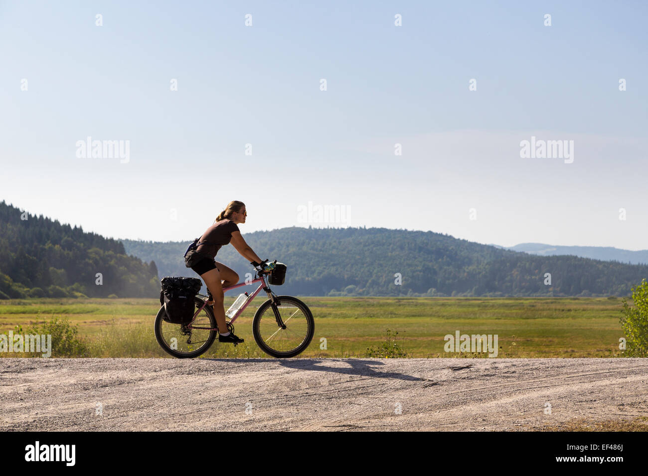 Donna ciclismo su strada di ghiaia, Cerknica, Slovenia Foto Stock