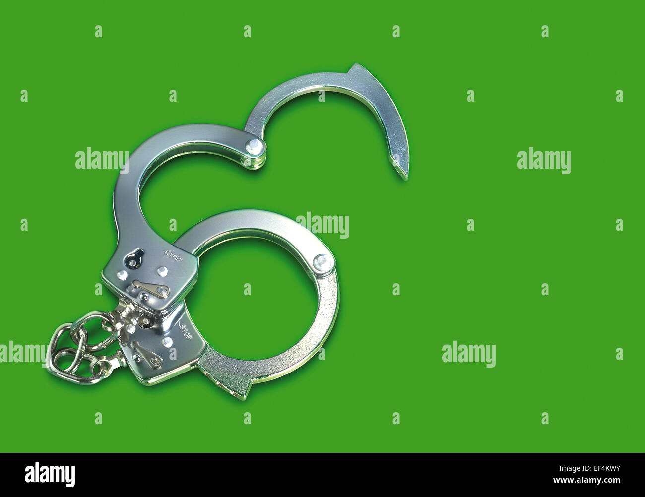 Una coppia di acciaio manette su uno sfondo verde Foto Stock