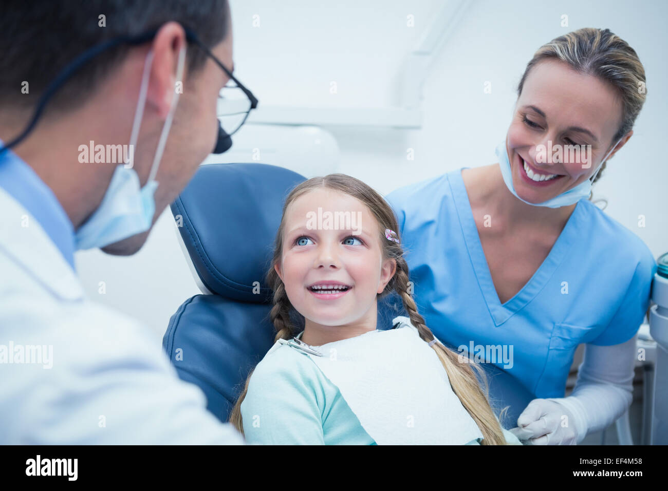 Dentista con assistente esaminando le ragazze denti Foto Stock