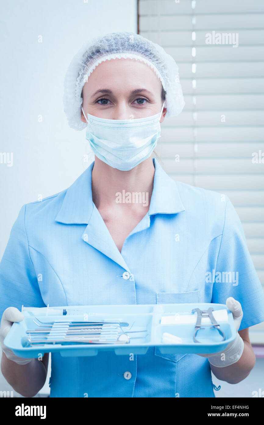 Dentista femmina nella mascherina chirurgica vaschetta di contenimento di strumenti Foto Stock