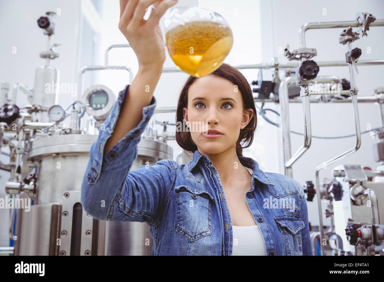 Elegante ragazza in camicia denim holding bicchiere di birra Foto Stock
