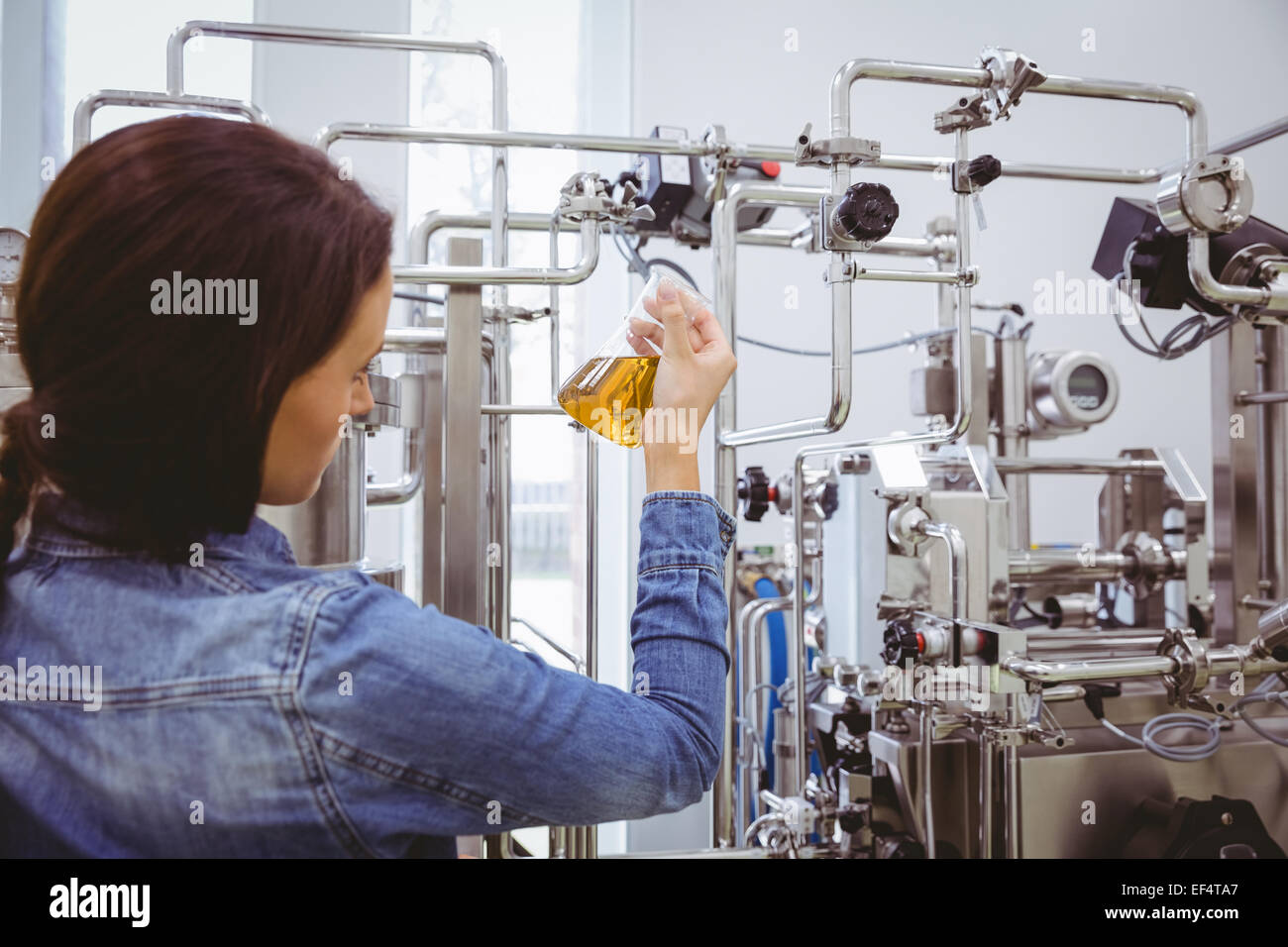 Elegante ragazza in camicia denim holding bicchiere di birra Foto Stock