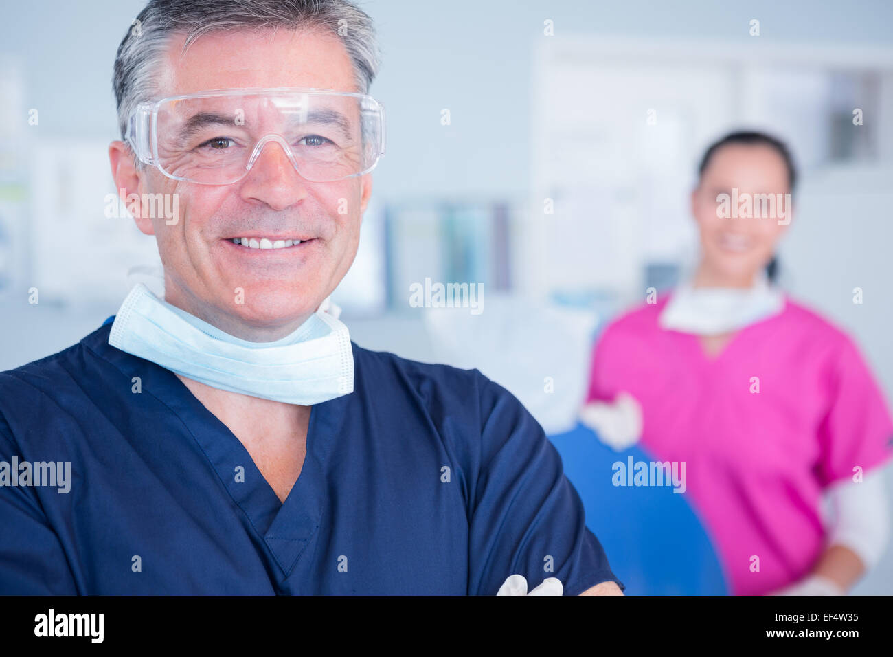 Sorridente dentista con gli occhiali di protezione Foto Stock
