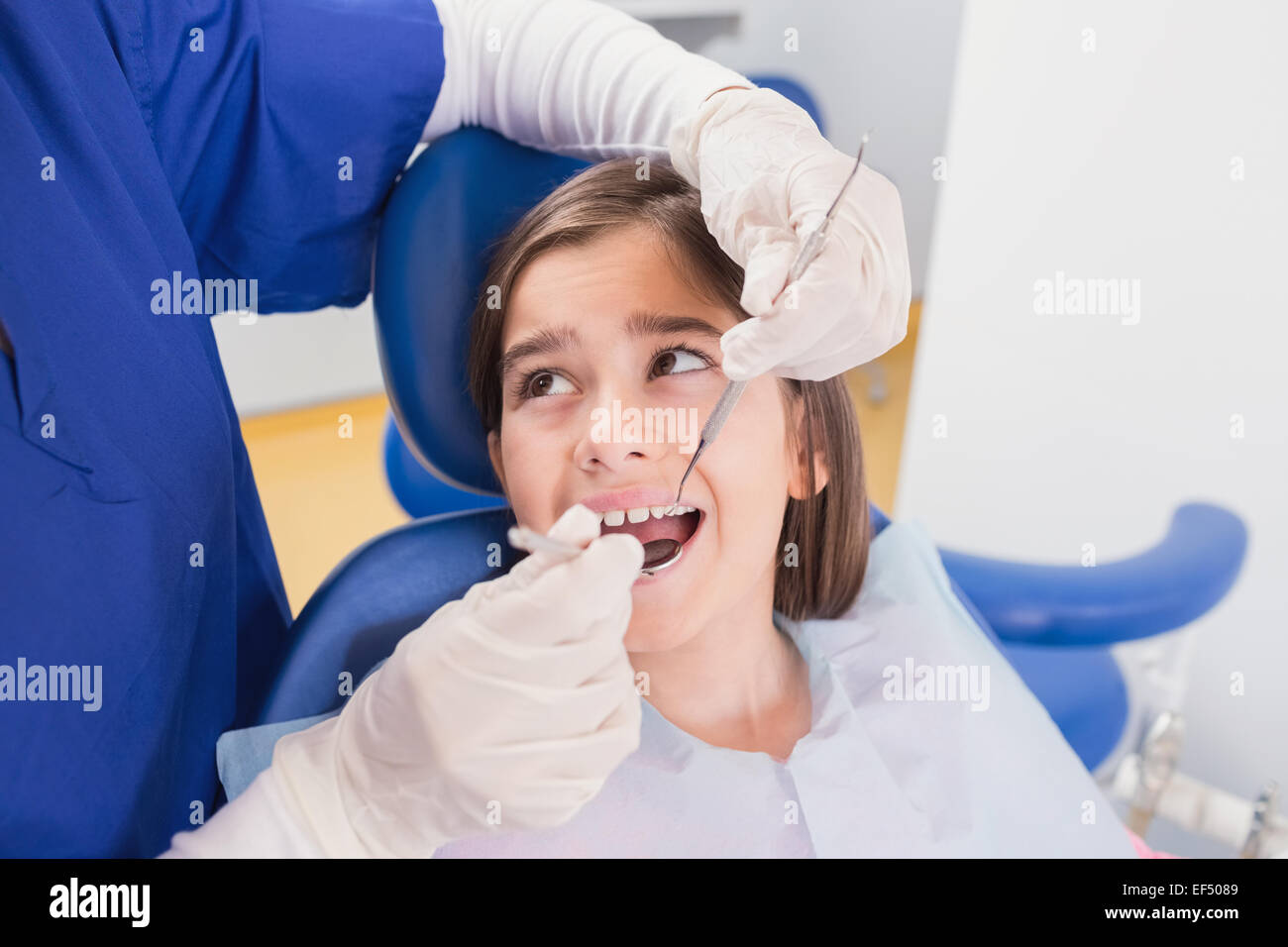Dentista pediatrico facendo esame a una paura paziente giovane Foto Stock