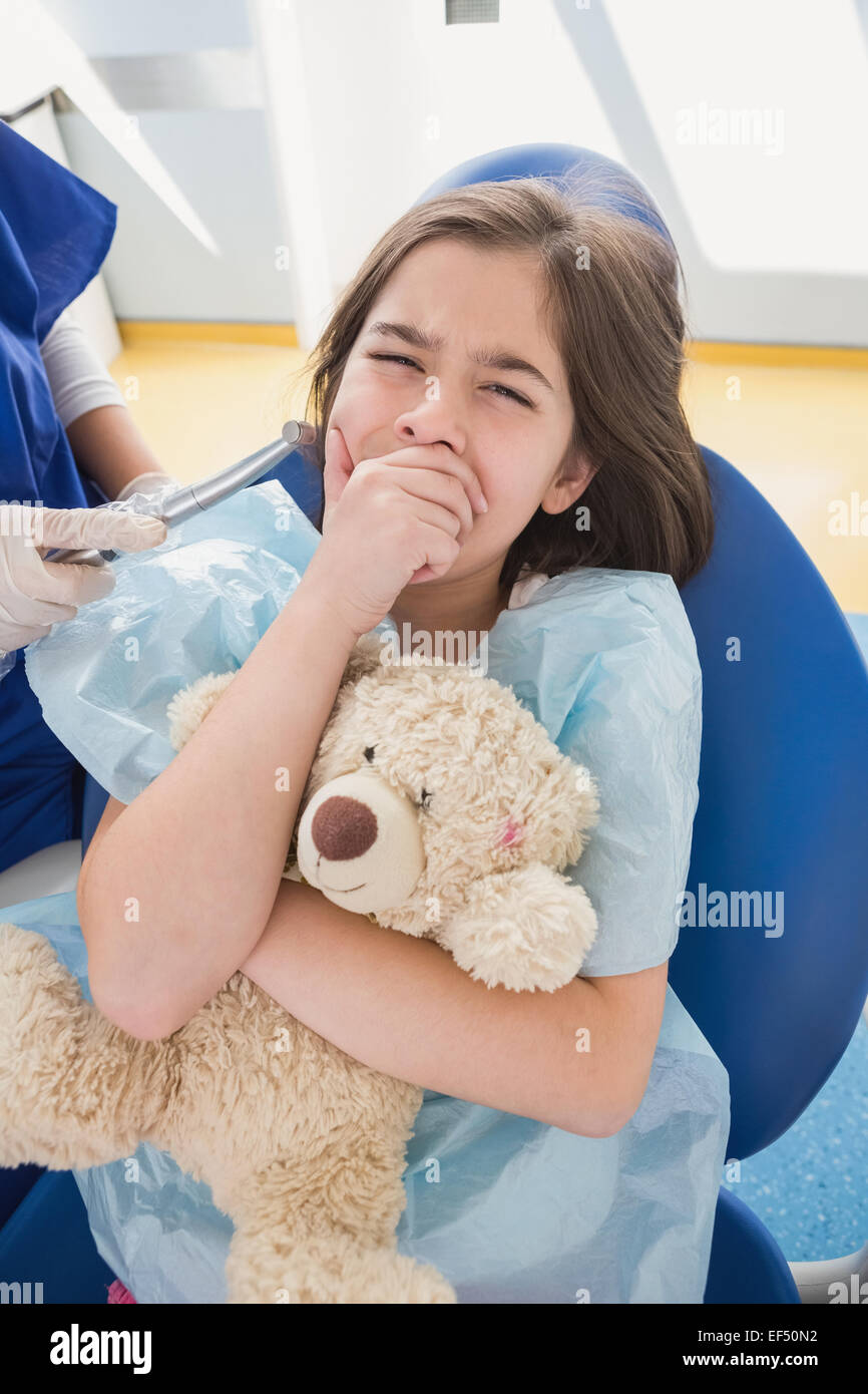 Spaventata paziente che copre la bocca e tenendo orsacchiotto Foto Stock