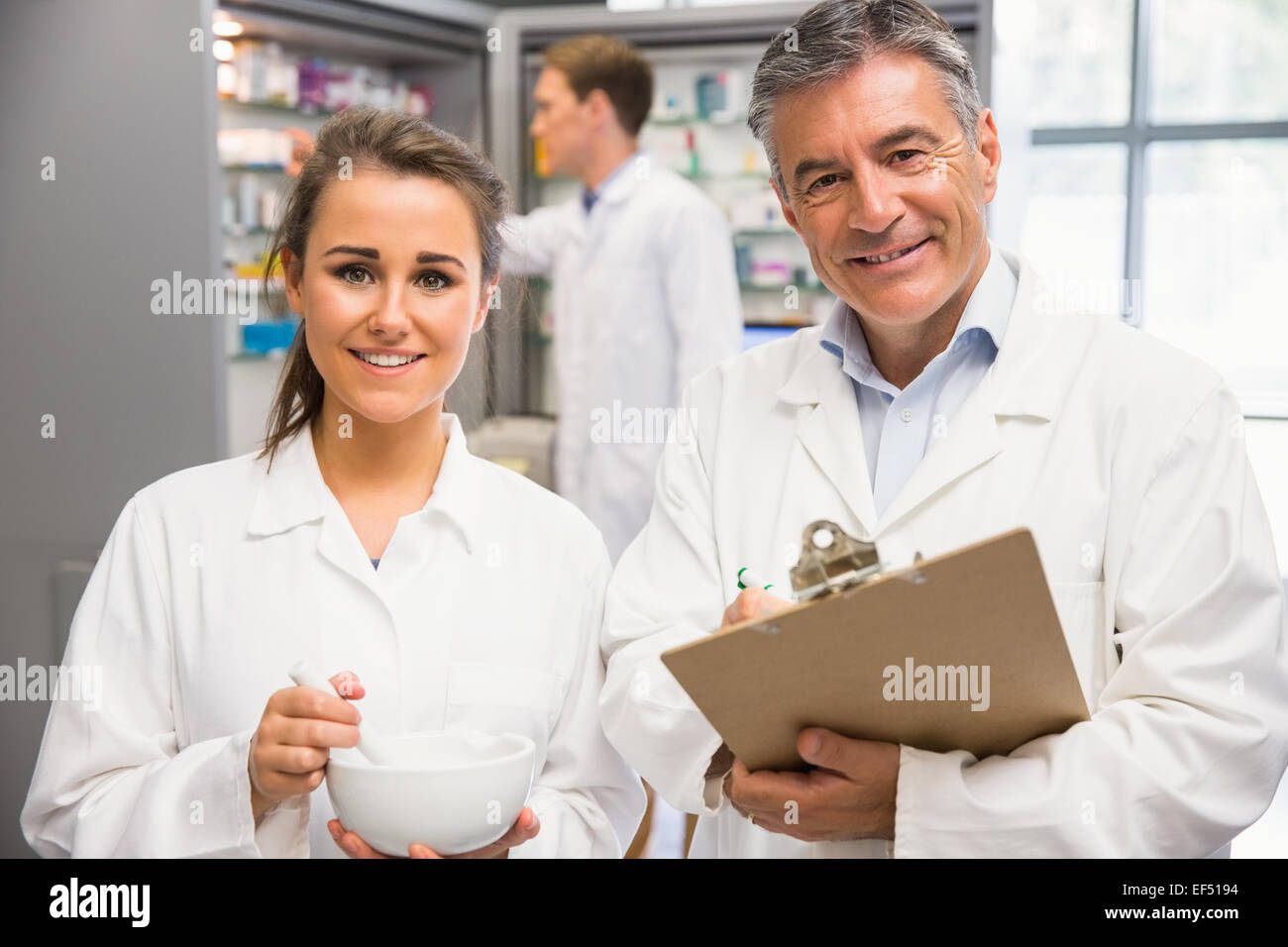 Junior farmacista la miscelazione di un farmaco con il suo senior Foto Stock