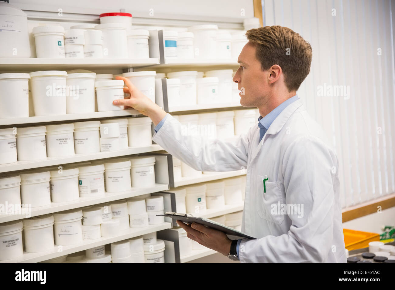 Bello il farmacista di prendere la medicina dal ripiano Foto Stock