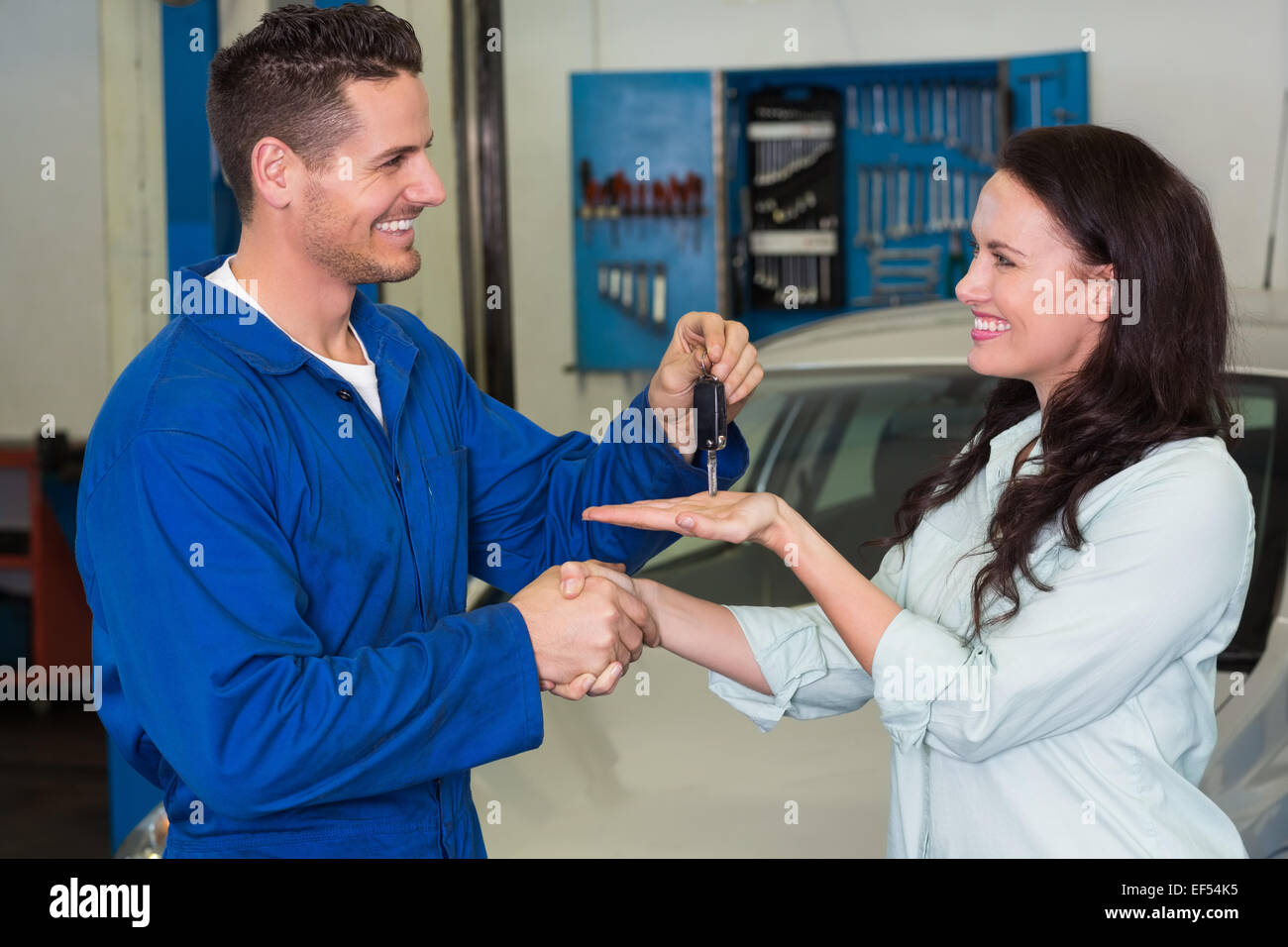 Il meccanico che dà le chiavi al cliente soddisfatto Foto Stock