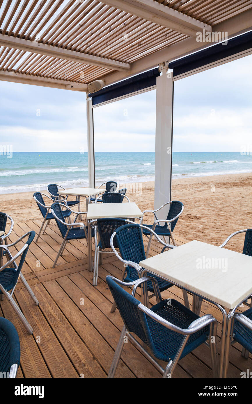 Aprire la barra di spazio interno con pavimento in legno e poltrone in metallo sulla spiaggia sabbiosa Foto Stock