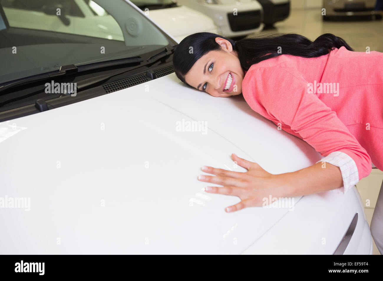 Donna sorridente abbracciando una vettura bianca Foto Stock